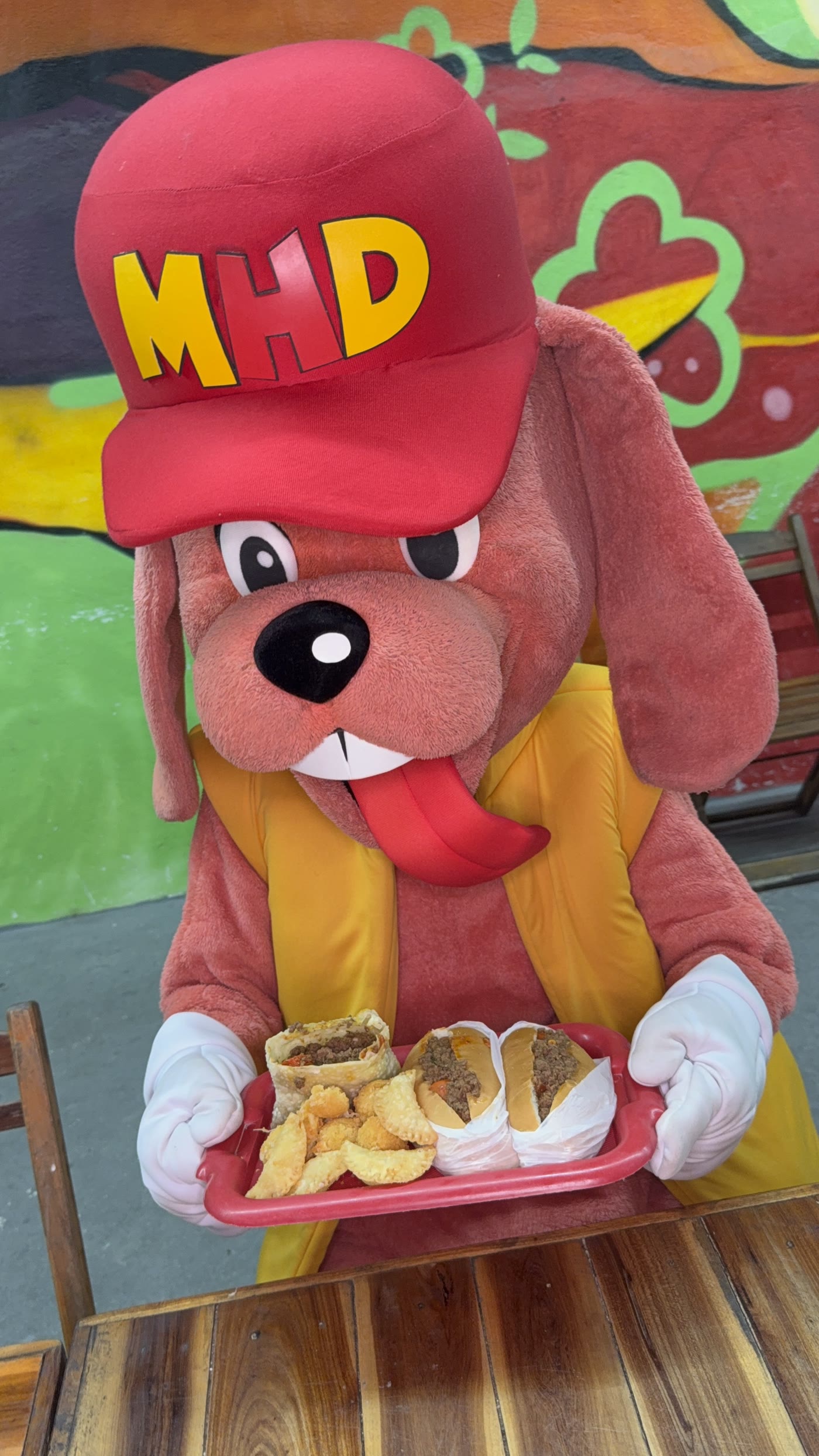 Doug segurando uma bandeja de hot dogs em frente à lanchonete